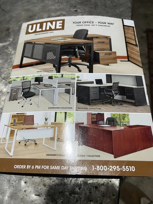 Large Uline product catalog placed on a wooden table, showing the cover and spine, illustrating unsolicited marketing materials